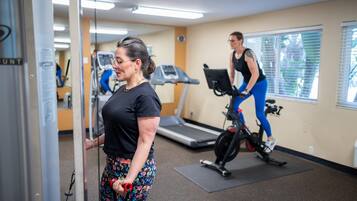 Un gimnasio con equipo de ejercicio, incluyendo cintas de correr y bicicletas estáticas.