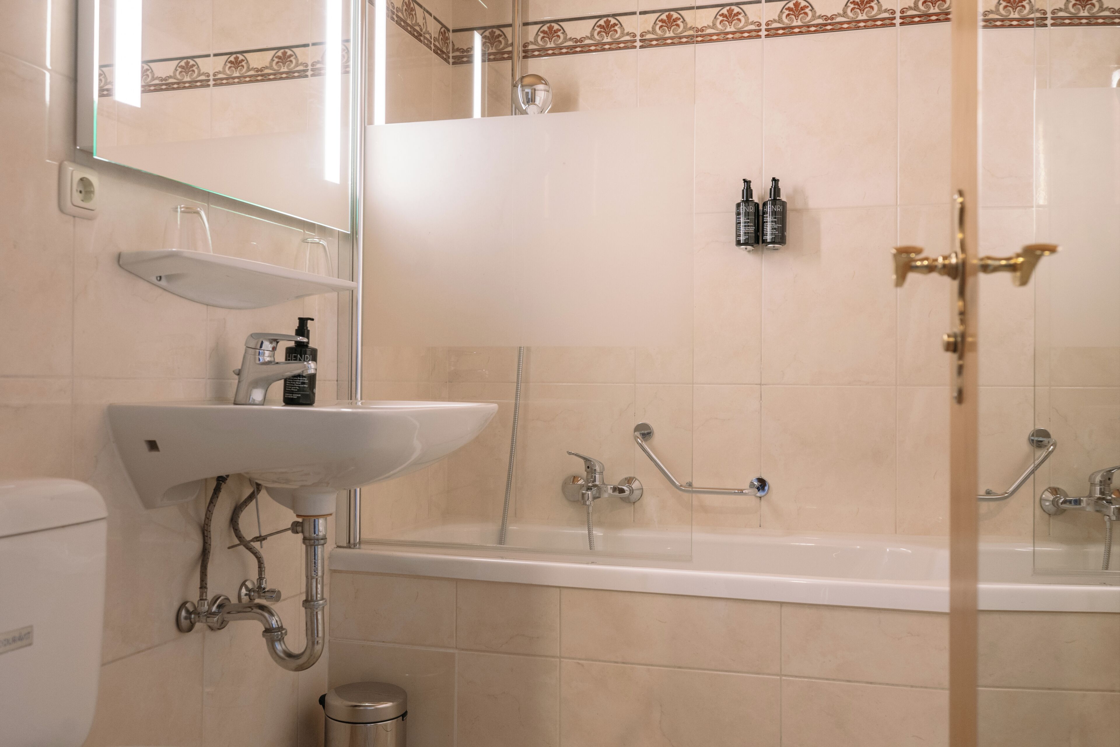 Une salle de bain équipée d’un lavabo, d’un miroir, d’une douche et de toilettes.
