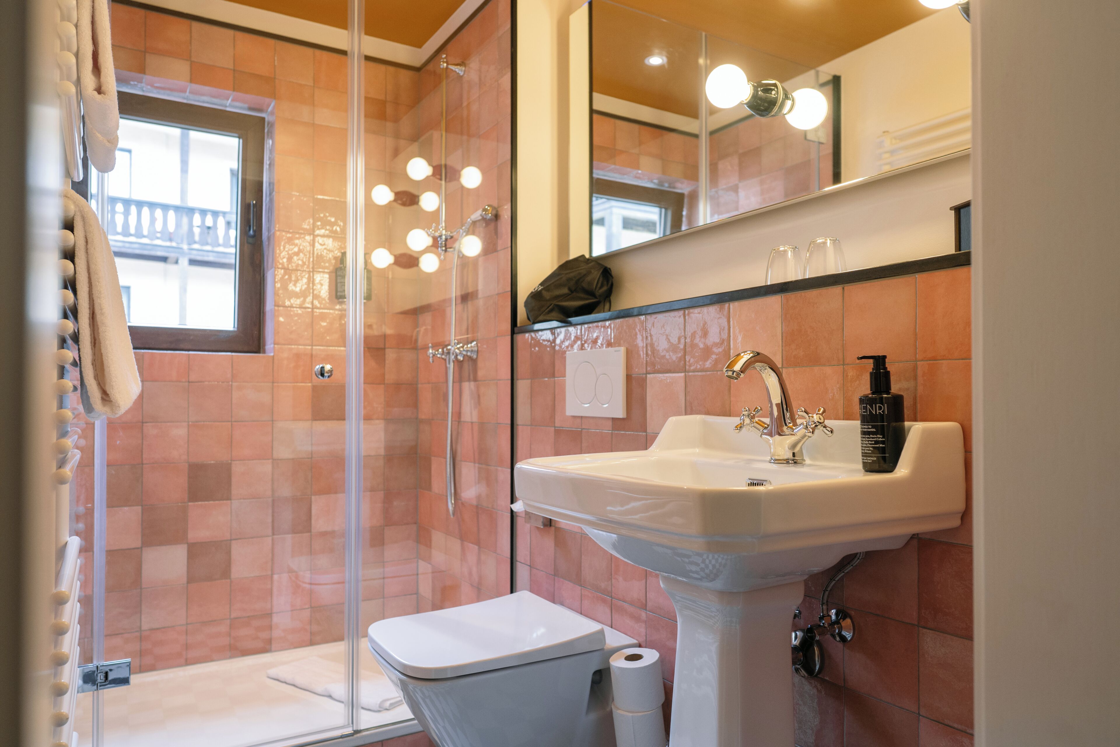 A bathroom with a glass shower enclosure, a white sink, and a mirror above it.