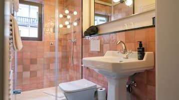 Ein Badezimmer mit einer Glasdusche, einem weißen Waschbecken und einem Spiegel darüber.