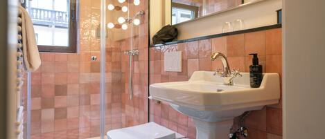A bathroom with a glass shower enclosure, a white sink, and a mirror above it.