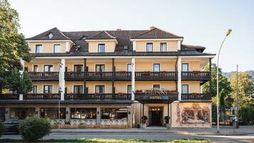A multi-story hotel with a yellow facade, balconies with flower boxes, and a sign reading 'HENRI HOTEL'.