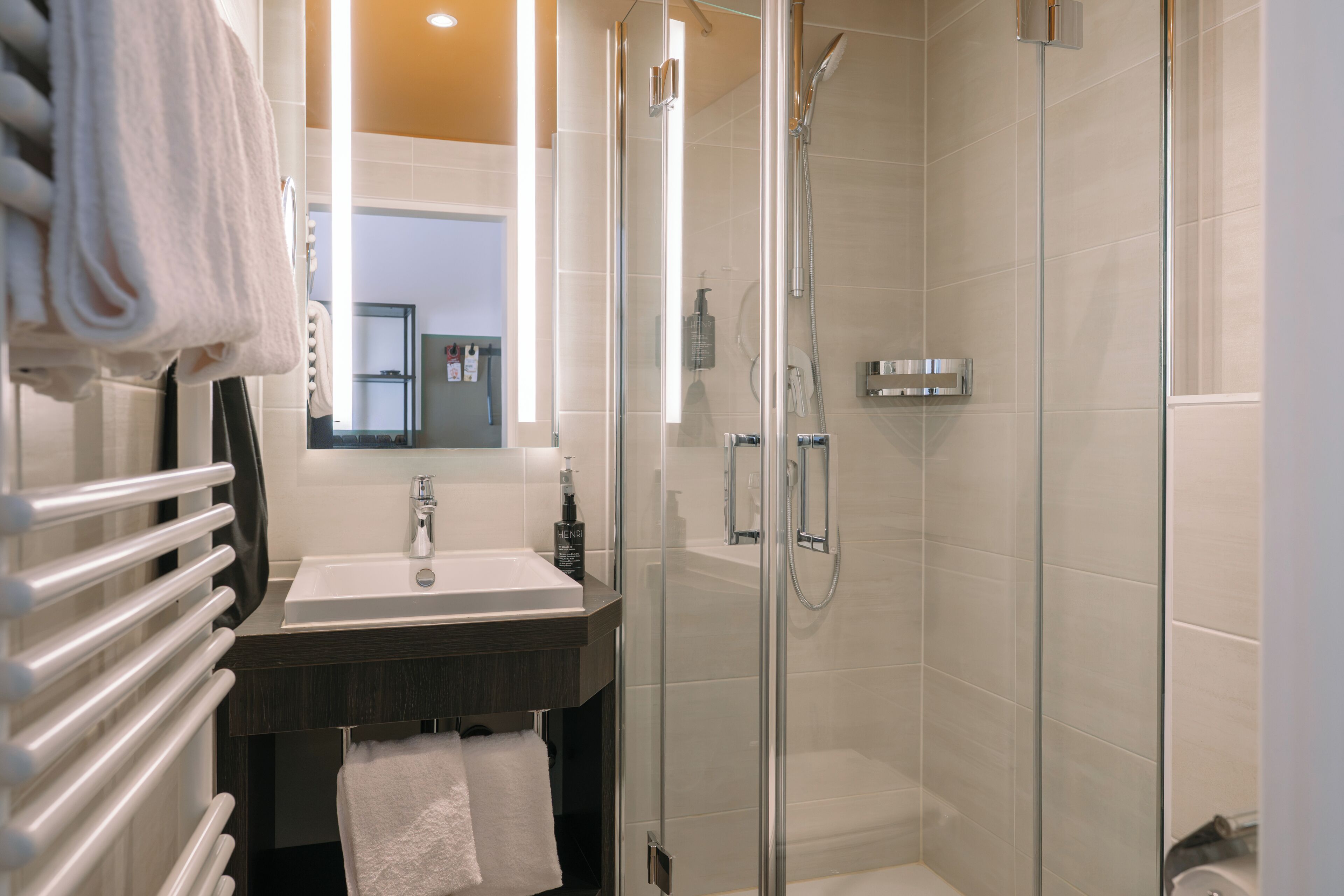 A modern bathroom with a glass-enclosed shower, a sink, and a towel rack.