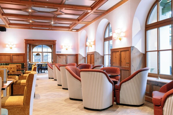 A hotel lobby with a high ceiling, arched windows, and a seating area with striped chairs.