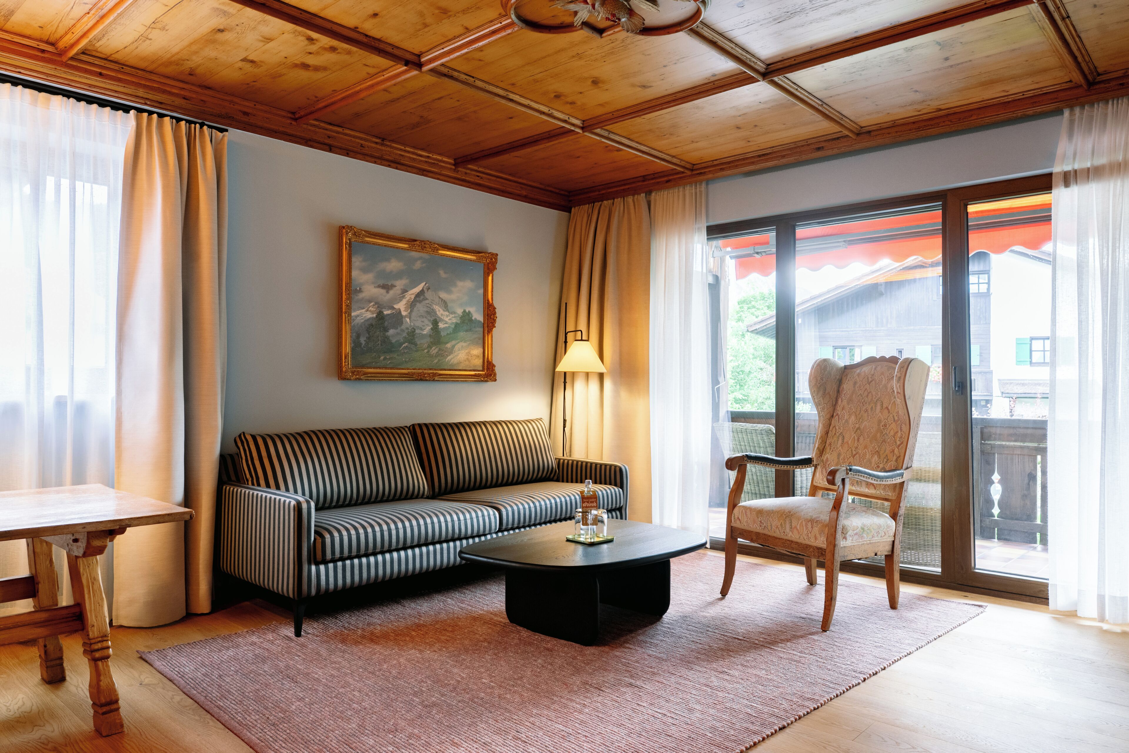 Una sala de estar con sofá, sillón, mesa de centro y un cuadro en la pared.