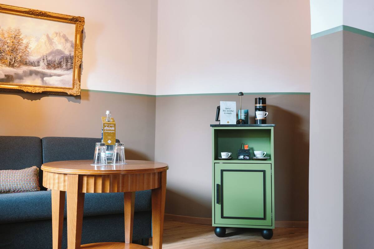 Une pièce chaleureuse avec une table en bois, un mini-bar vert et un tableau accroché au mur.