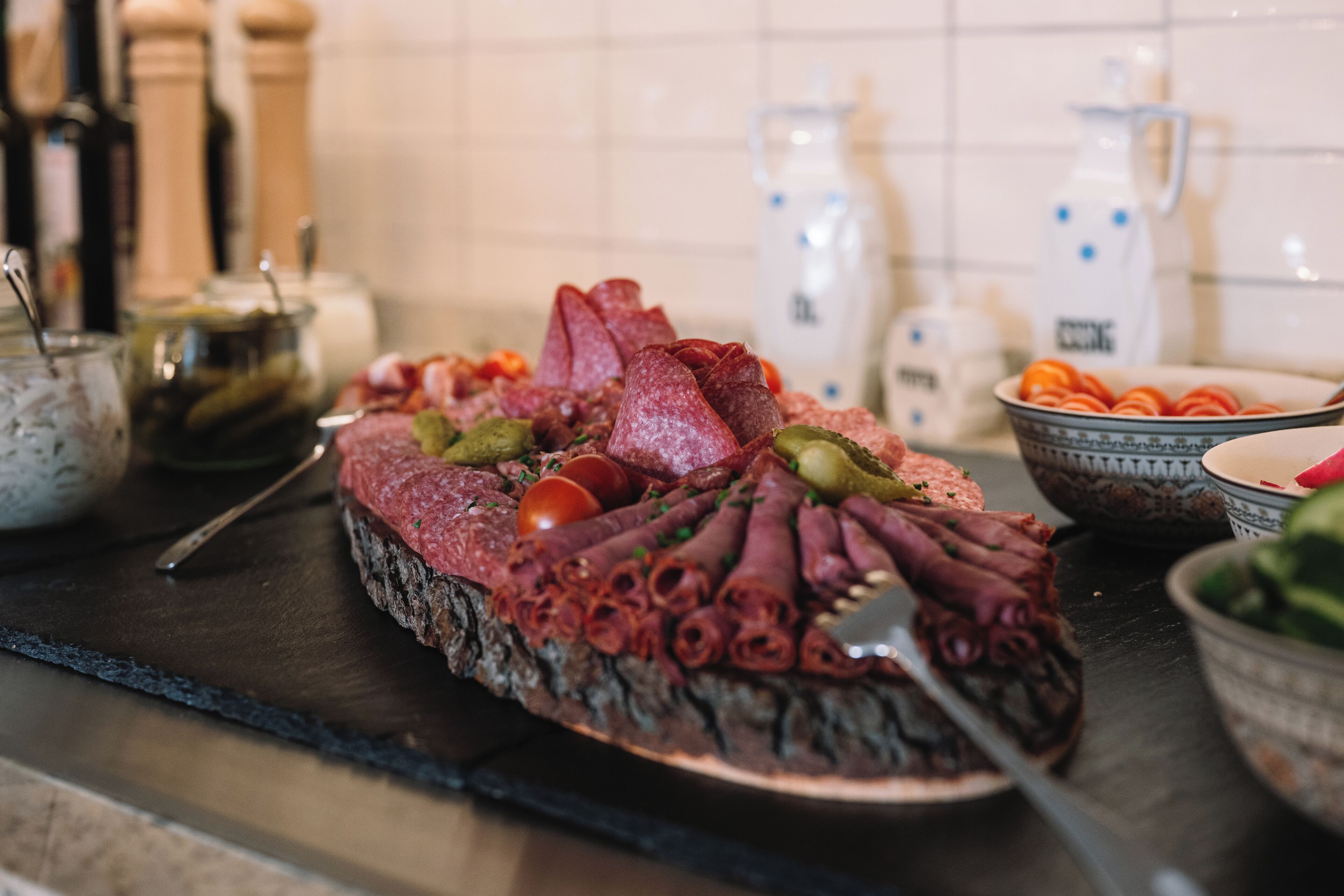 A charcuterie board with various meats and vegetables.
