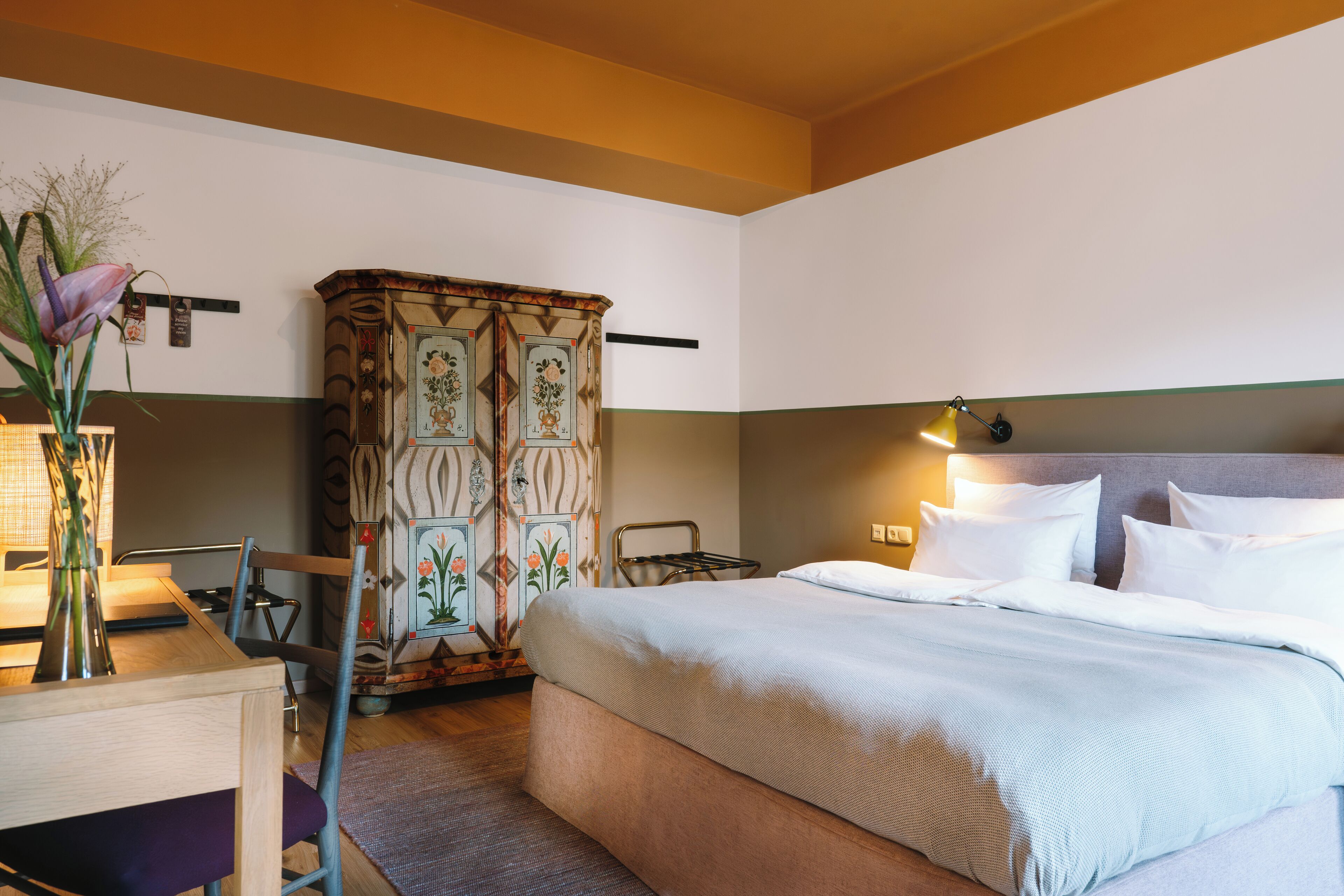Habitació d'hotel amb llit, escriptori, cadira i armari.