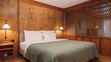 A wooden-paneled room with a bed, two bedside lamps, and a lattice partition.