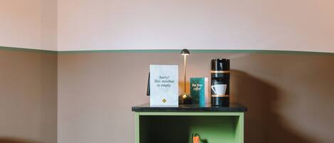 En kaffestation med en skylt, en kaffemaskin, koppar och en lampa.