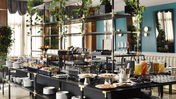 Montaje tipo bufé con diversos alimentos, bebidas y una decoración floral.