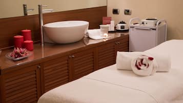 Ein Hotelzimmer mit einem großen weißen Waschbecken, Holzschränken, einem Bett mit weißem Handtuch und einem kleinen Heizgerät auf der Ablagefläche.