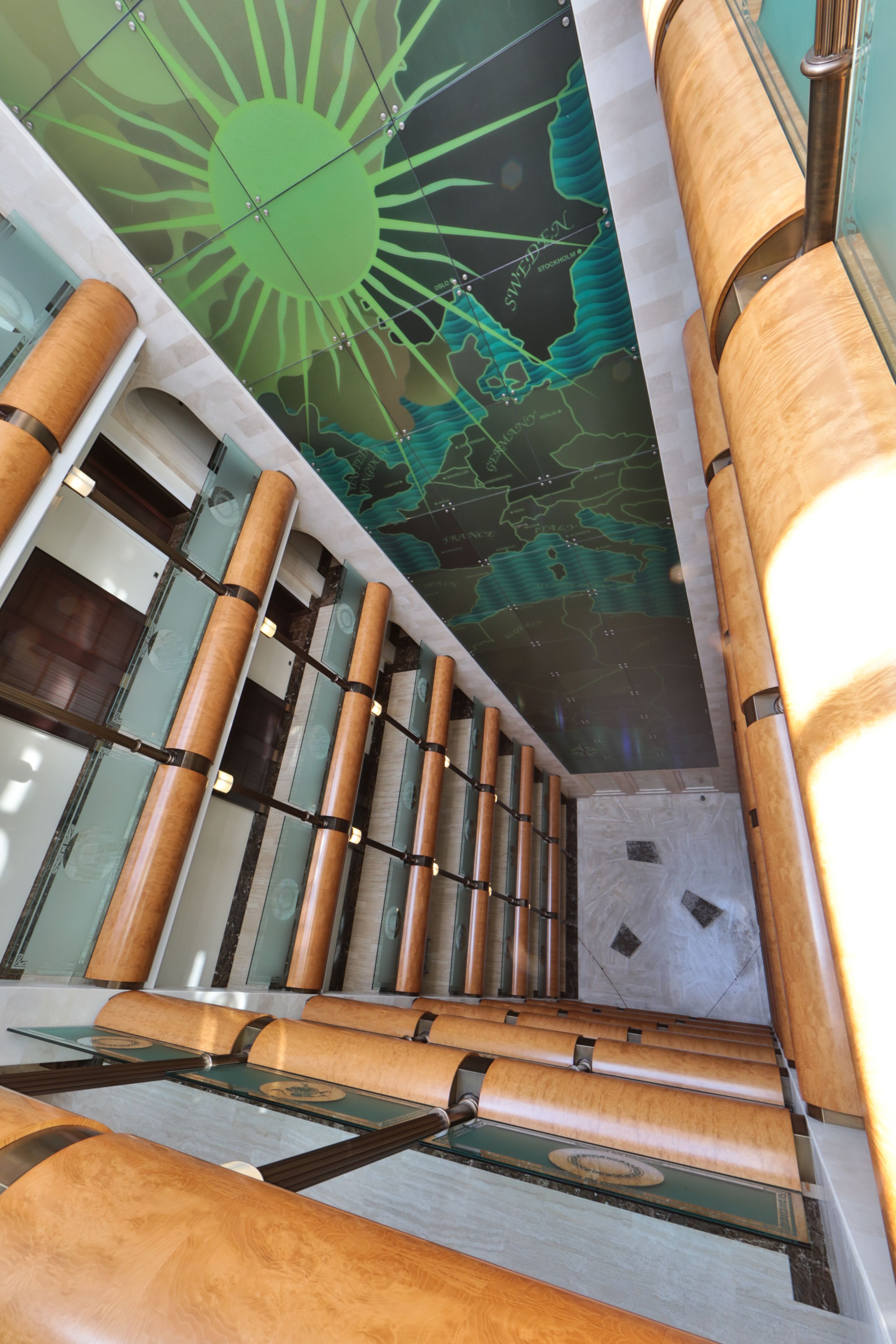 A modern interior with a unique ceiling design, cylindrical columns, and a glass floor.