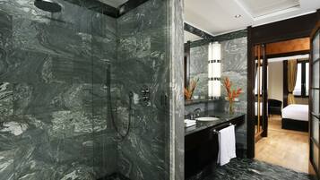 Un bagno moderno con doccia in marmo, uno specchio grande e un lavandino con asciugamano.