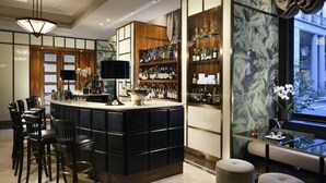 Zona de bar con mostrador negro, varias opciones de asiento y una amplia exhibición de vinos.