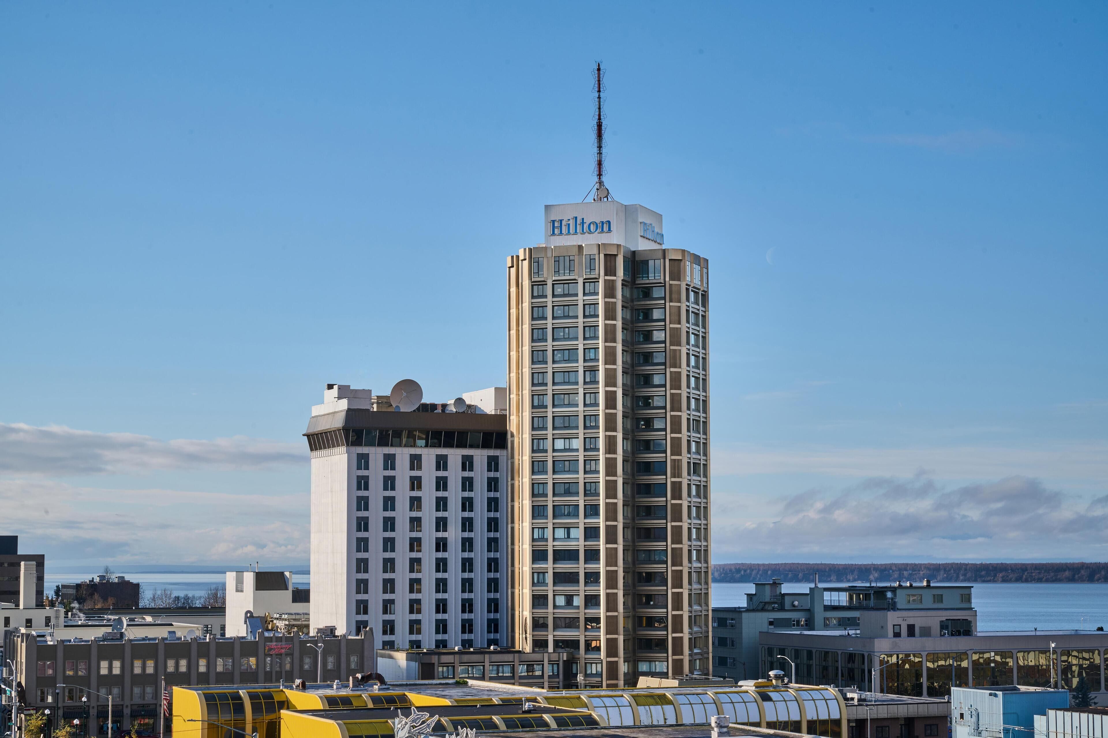 A tall hotel with a prominent antenna and a view of the water.