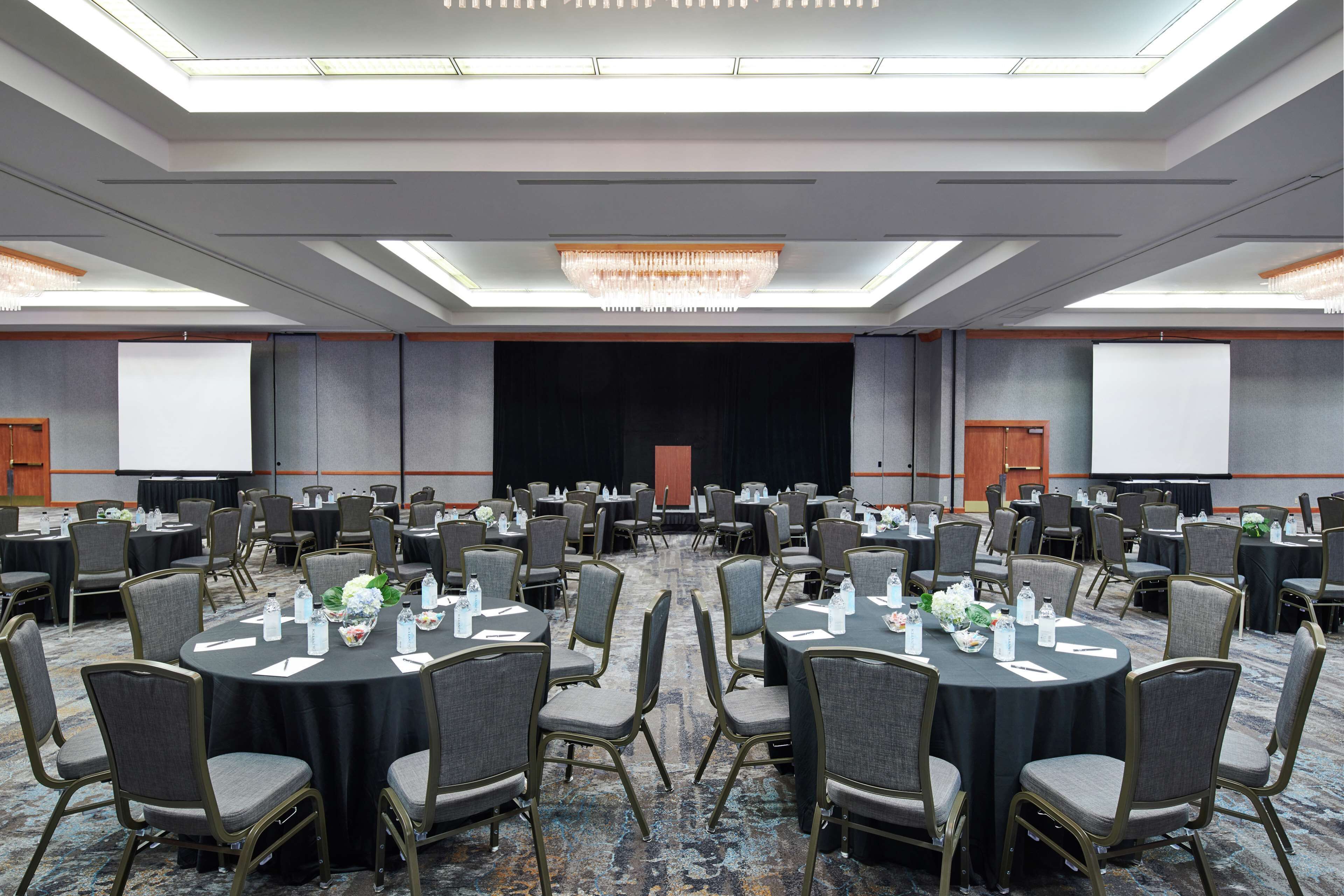 A conference room with round tables, chairs, and a stage.