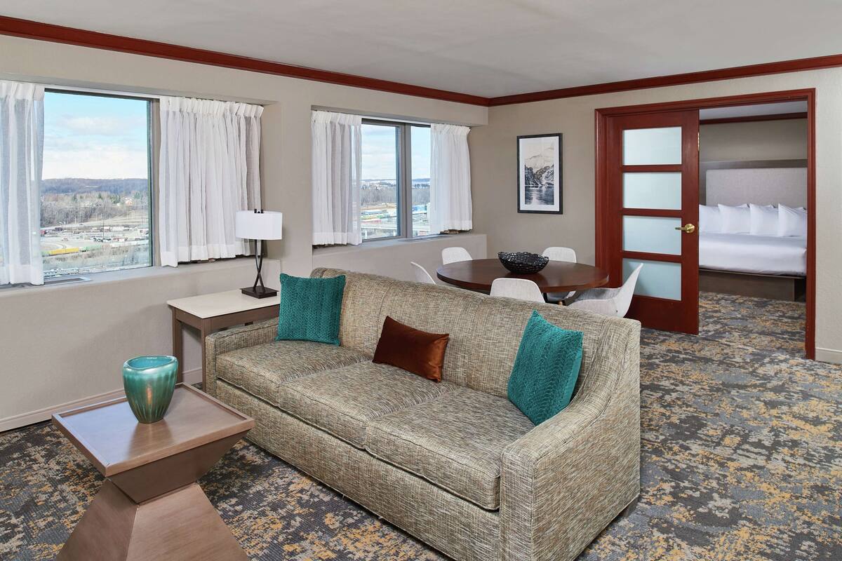 A hotel room with a sofa, a dining table, and a bed.
