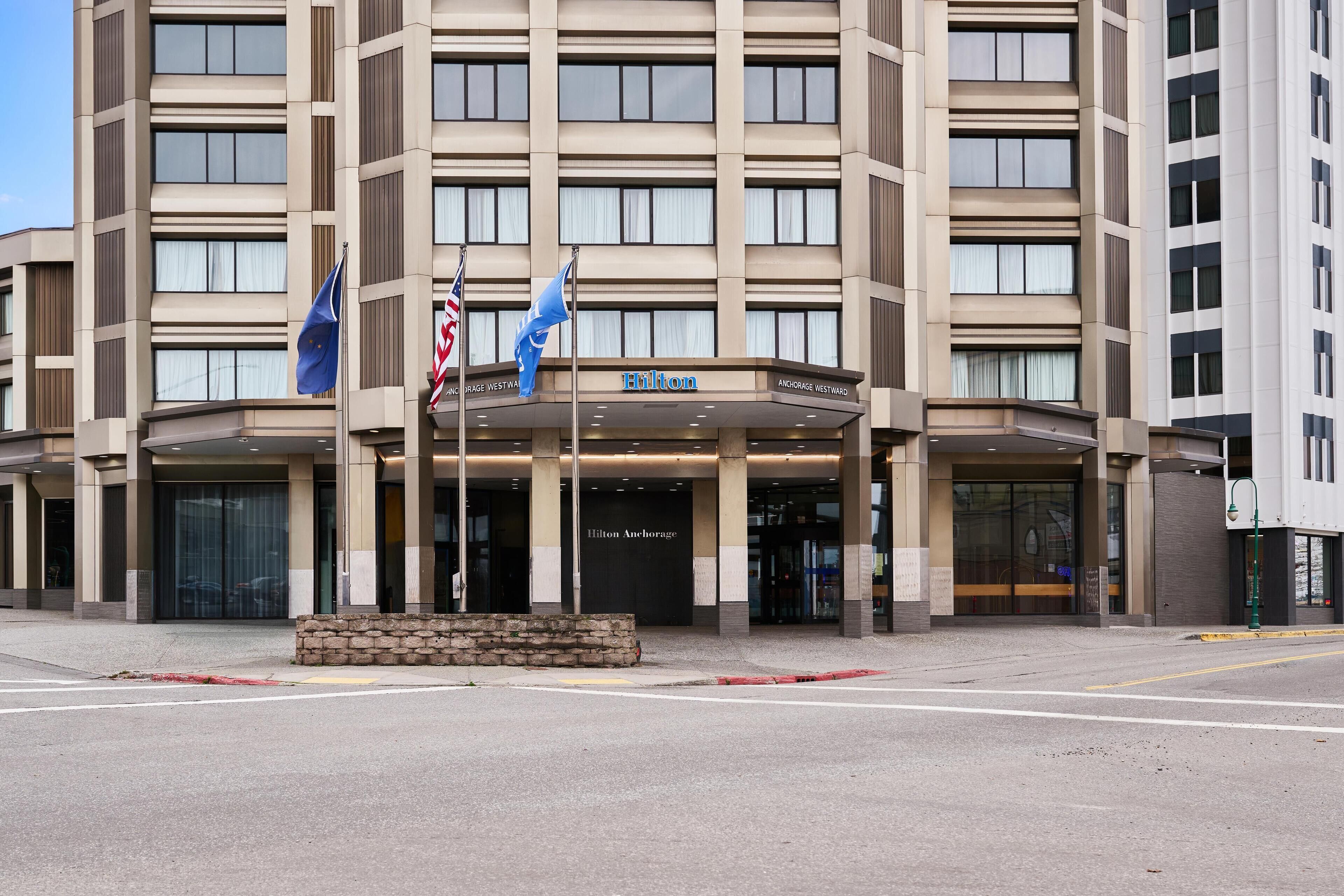 A multi-story hotel with a modern facade, featuring a prominent entrance and a sign that reads "Hilton Anchorage."