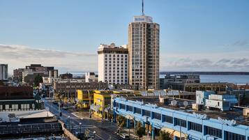 A tall hotel with a prominent antenna, surrounded by various buildings and a body of water in the background.