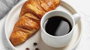 A croissant and a cup of coffee on a plate.