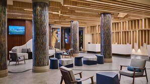 A modern lobby with large pillars, seating areas, and a reception desk. - Hilton Anchorage (Anchorage)