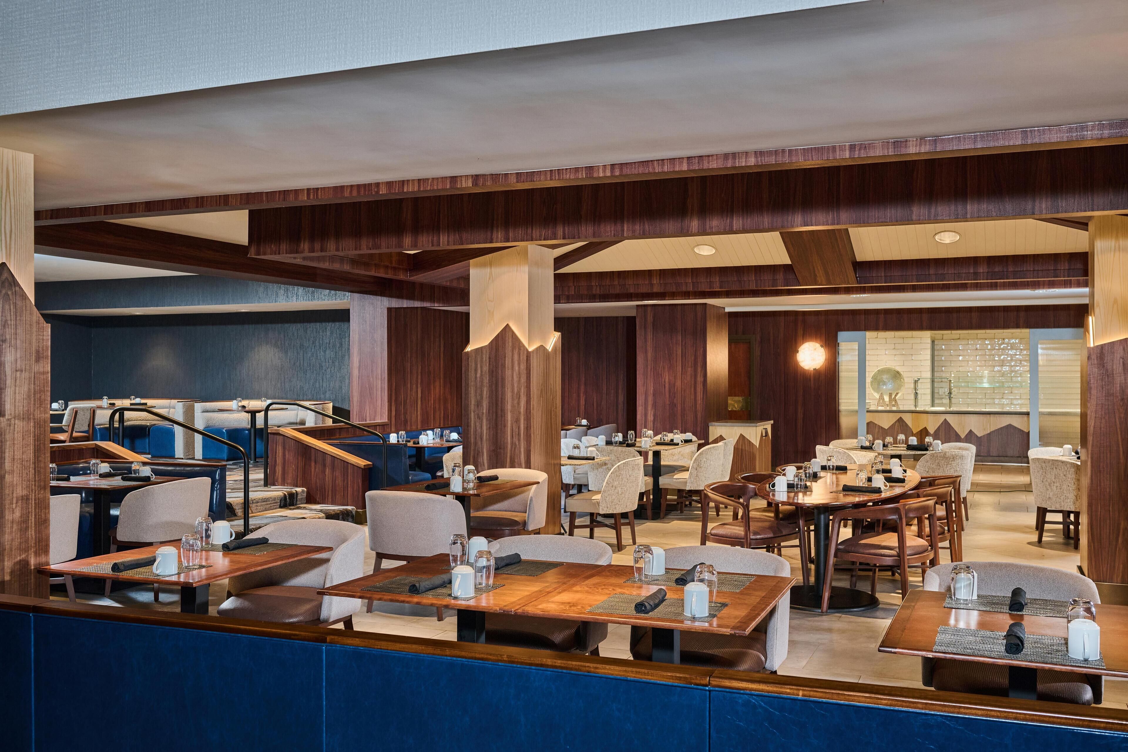 En modern hotellobby med träpanel, flera sittgrupper och ett stort fönster med utsikt.