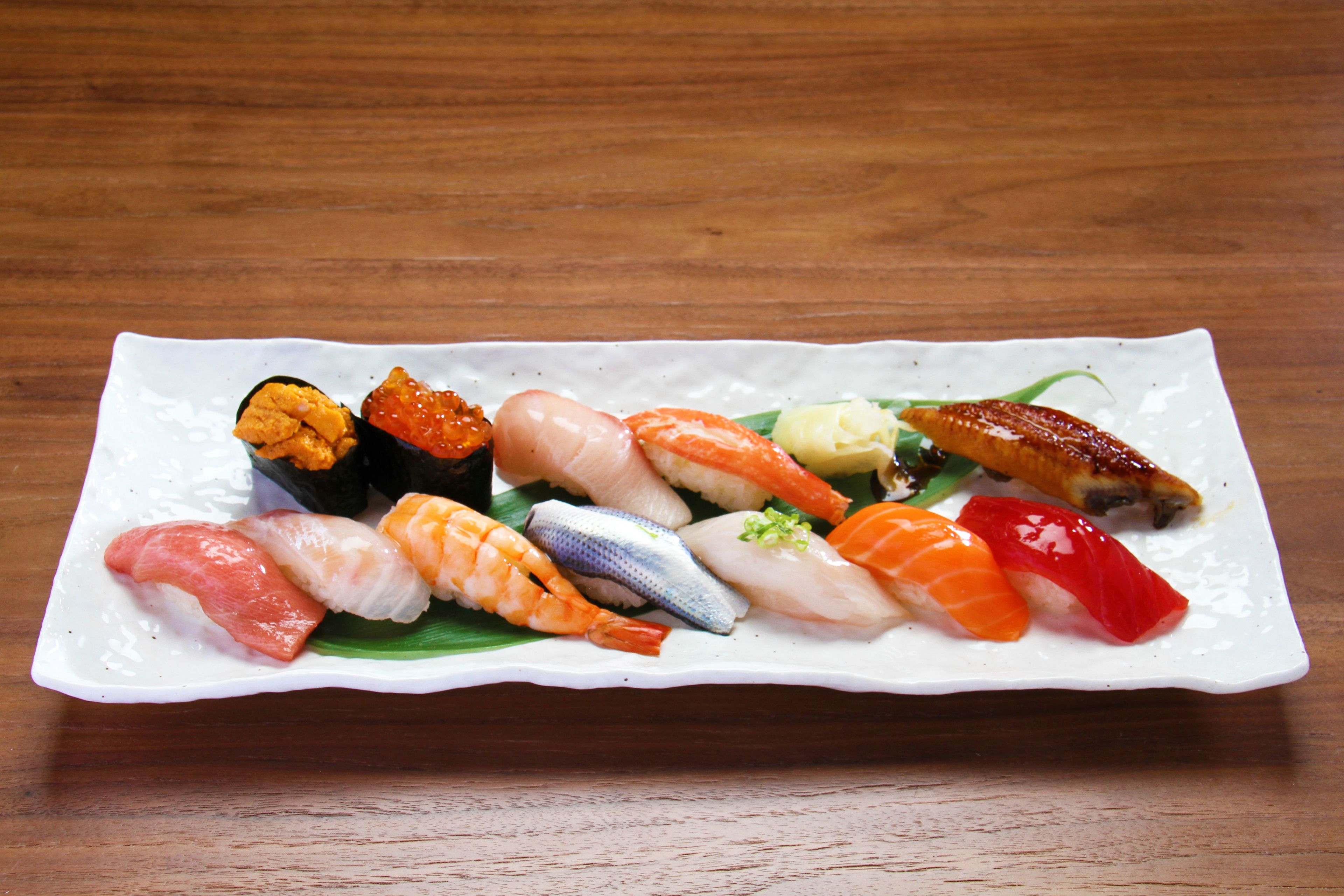 A variety of sushi on a rectangular white plate.