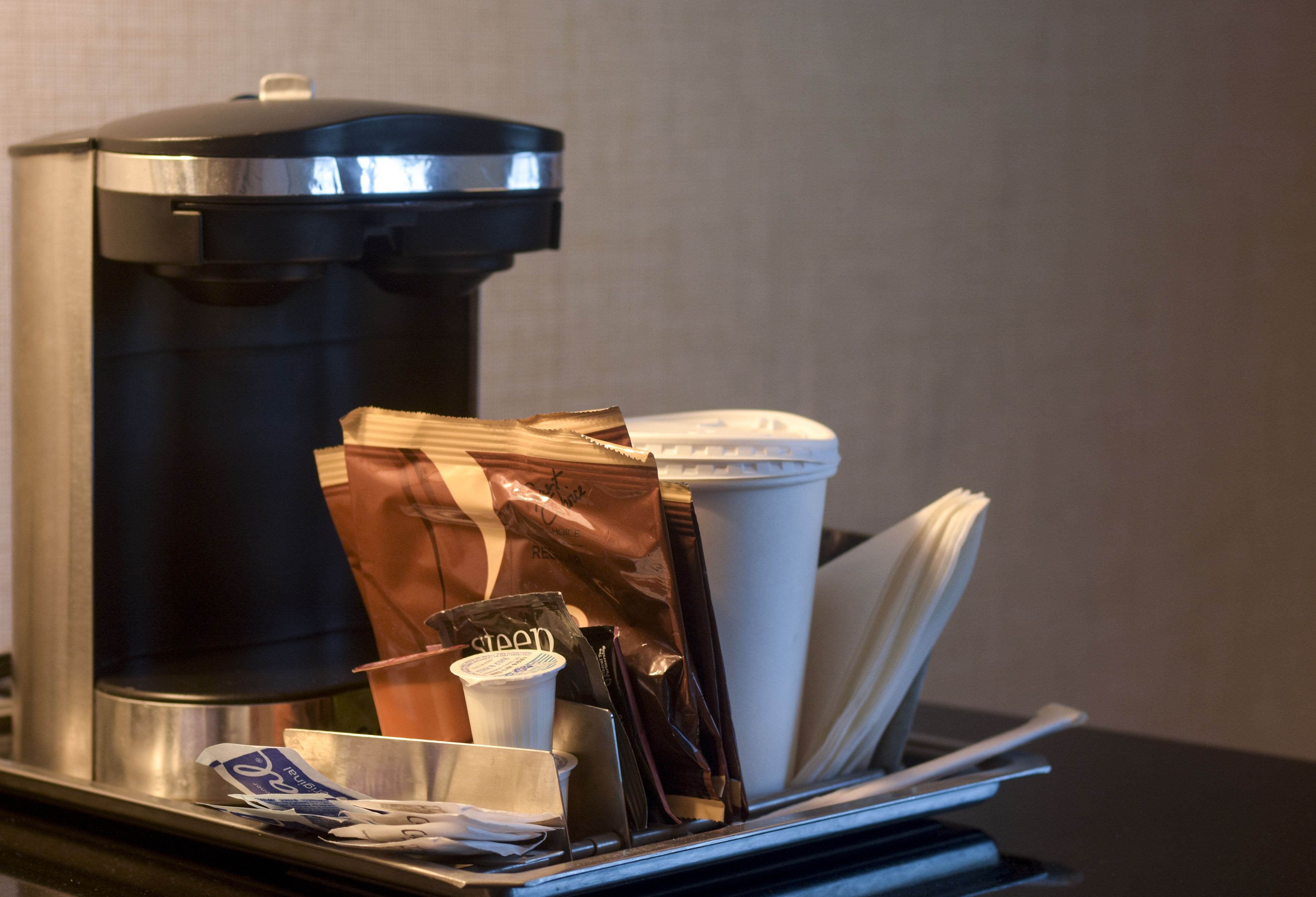 A coffee machine with disposable cups and a trash bin.