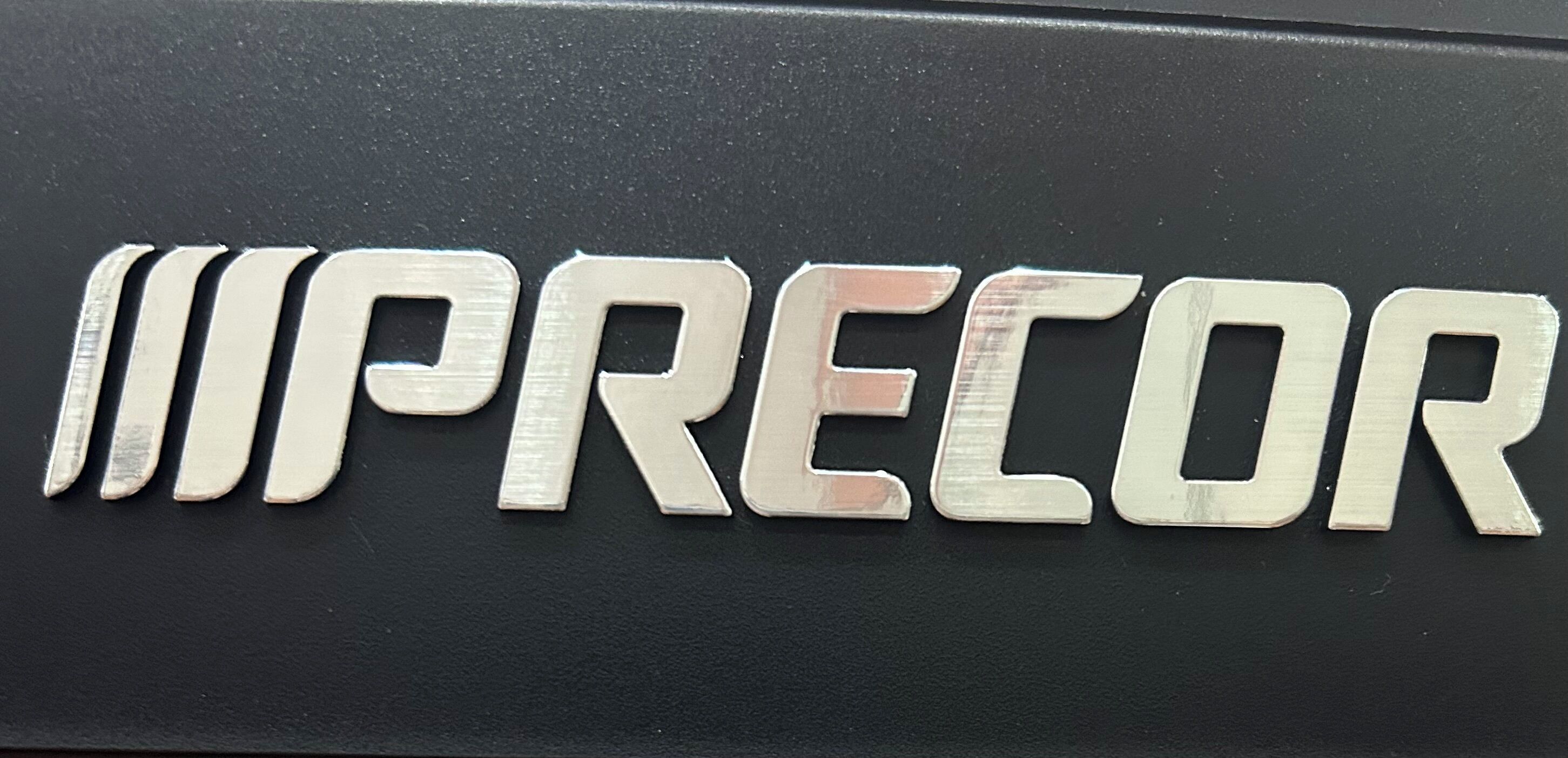 A metallic sign with the word "PRECOR" in capital letters.