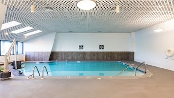 Ein Innenpool mit modernem Deckenbau, deutlich markiertem Poolbereich und einem sichtbaren Rettungsschwimmerstuhl.