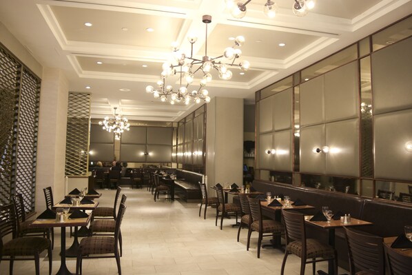 Un restaurant au décor moderne, agrémenté d’un lustre, de tables en bois et de chaises rembourrées.