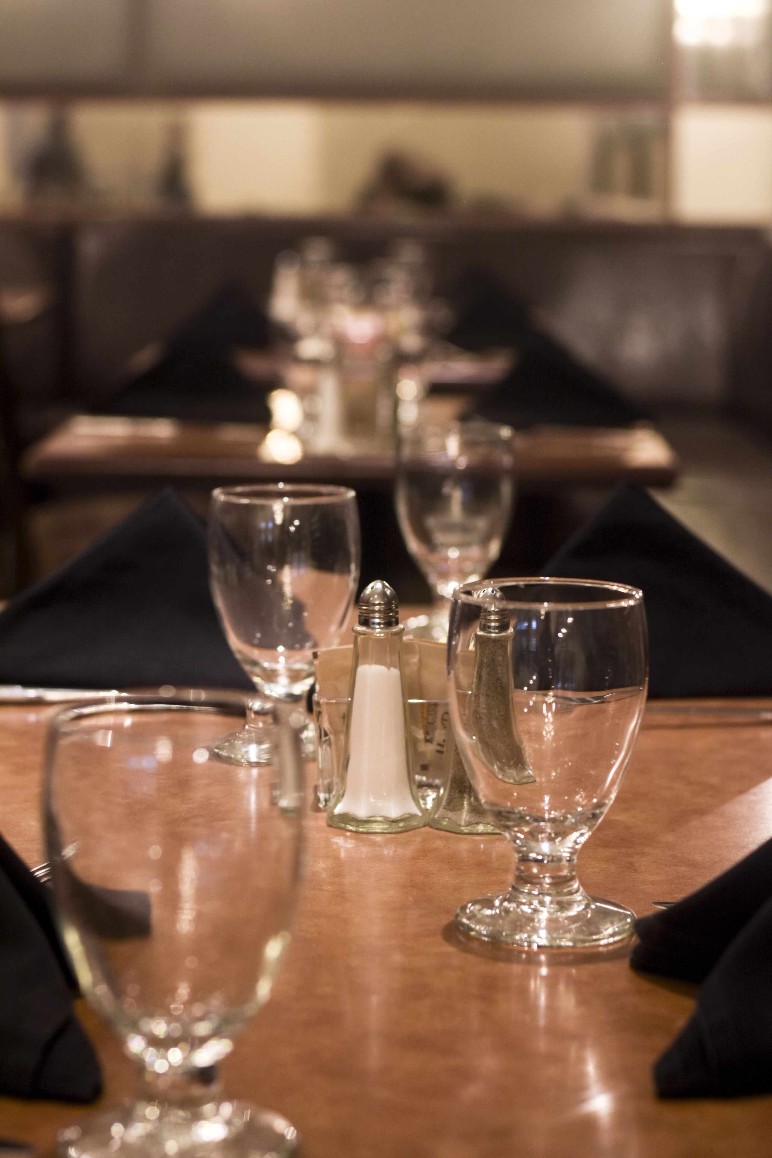 A dining table set with clear glassware, a salt shaker, and a candle.