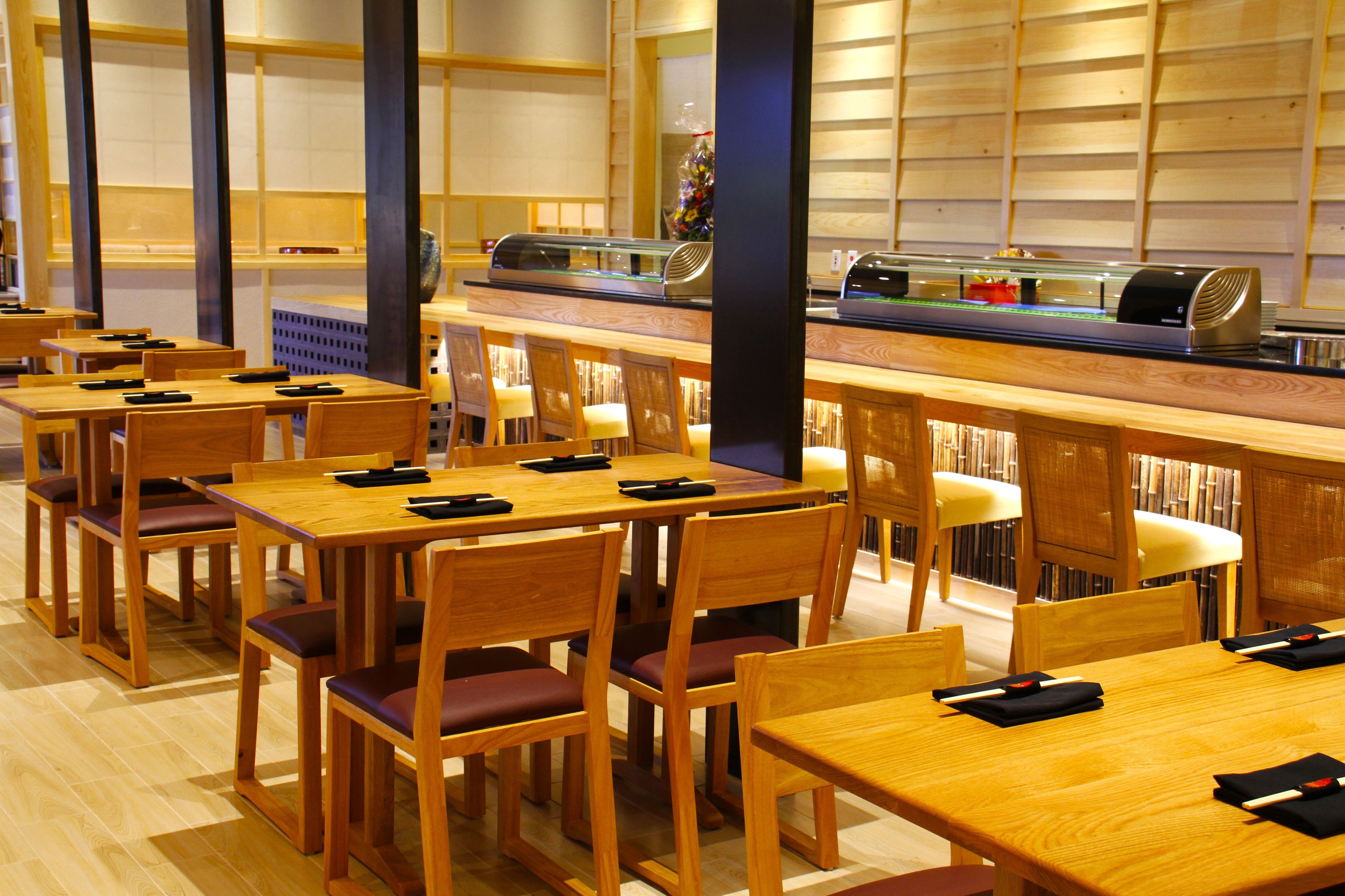 A restaurant with wooden tables and chairs, a buffet counter, and a wall with shelves.