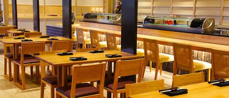 A restaurant with wooden tables and chairs, a buffet counter, and a wall with shelves.