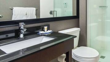A modern bathroom with a glass shower enclosure, a white toilet, and a sink with a black countertop.