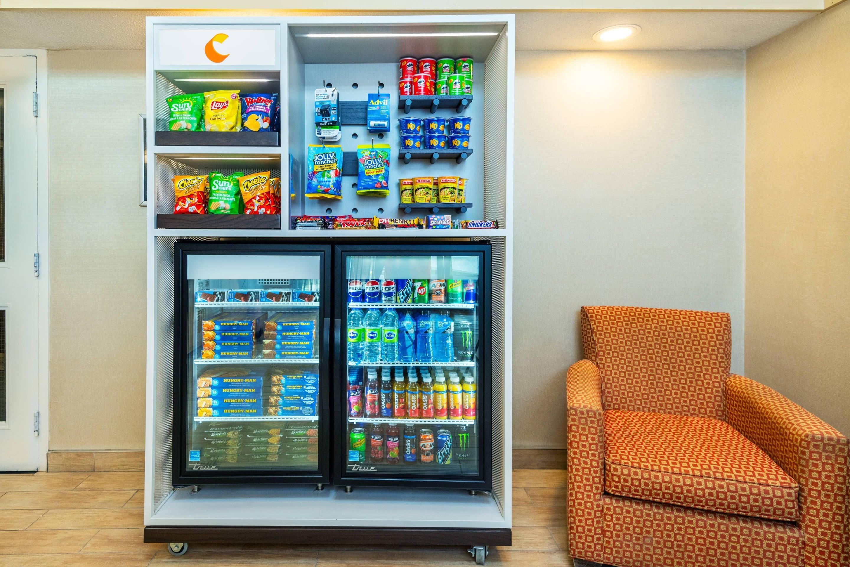 A vending machine with snacks and drinks, a chair, and a door.