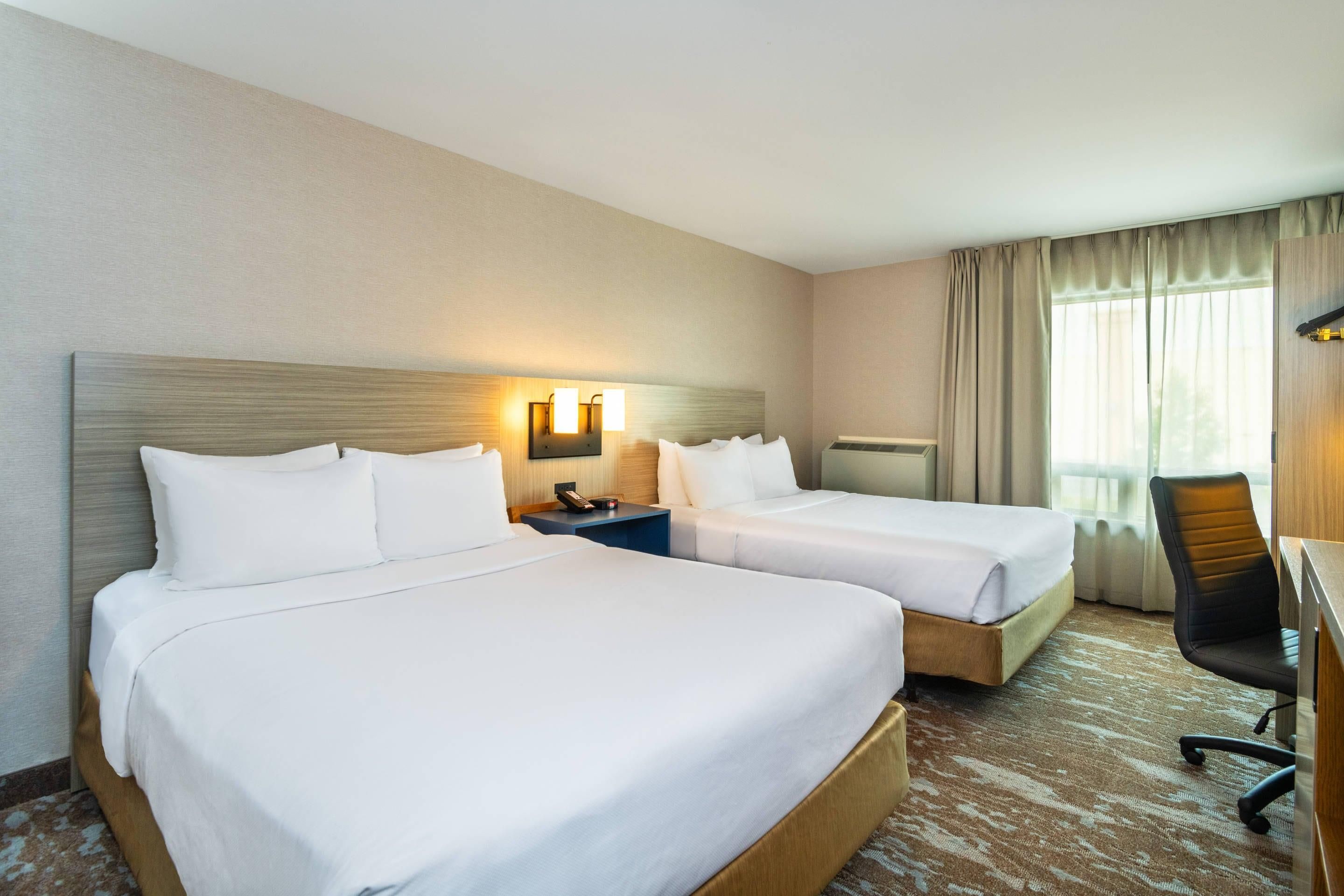 Une chambre d’hôtel avec deux lits, un bureau et une chaise.