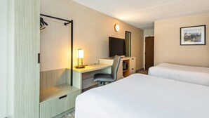 Habitación de hotel con cama, escritorio, silla y un espejo grande.