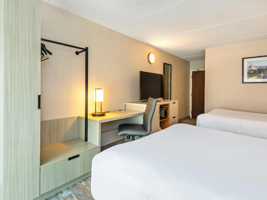 Una camera d'albergo con un letto, una scrivania, una sedia e uno specchio grande.