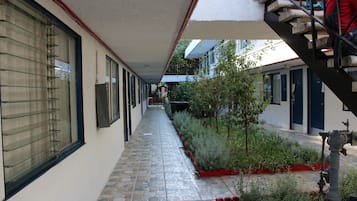 Un estrecho pasillo empedrado con una escalera a la derecha, flanqueado por edificios con ventanas y puertas.