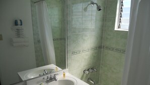 A bathroom with a sink, mirror, shower, and bathtub. - Los Angeles Adventurer All Suite Hotel at LAX (Inglewood)