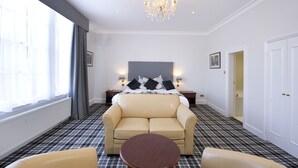 A hotel room with a large bed, a sofa, a round table, and a chandelier. - The Royal George Hotel (Perth)