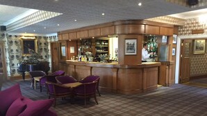 A bar area with wooden paneling, a piano, and purple chairs. - The Royal George Hotel (Perth)