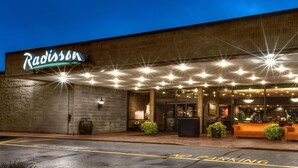A building with a sign reading 'Radisson' and a reception area with a counter and seating. - Radisson Hotel Corning (Corning)