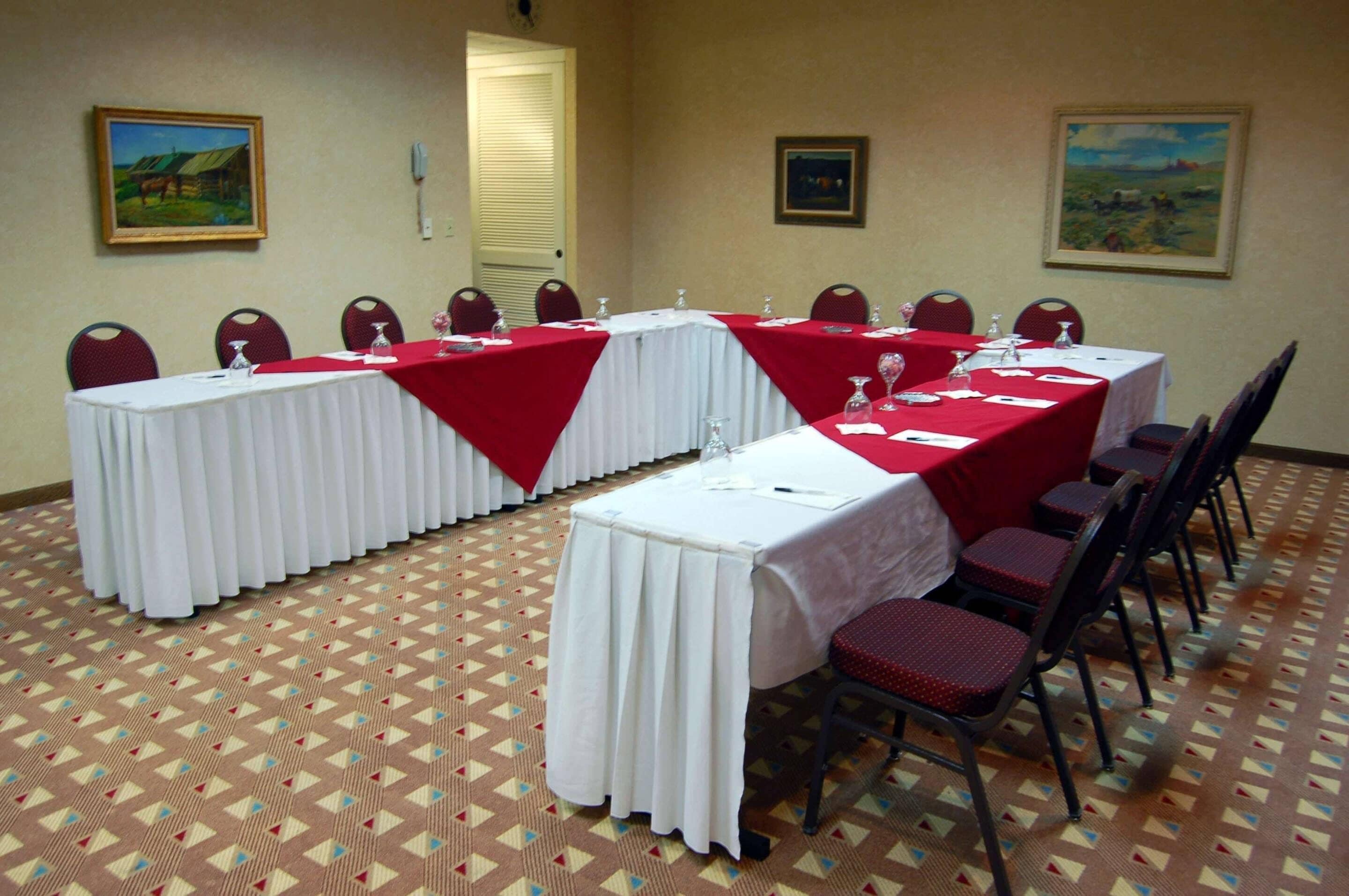 Une salle de conférence avec des tables disposées pour les réunions, des chaises placées autour, et des œuvres d’art accrochées aux murs.