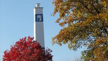 A tall white tower with a blue and white emblem, surrounded by autumn-colored trees.