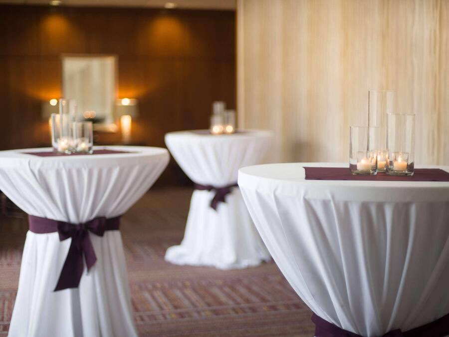 Three round tables with white tablecloths and purple sashes, each with candles and glassware.