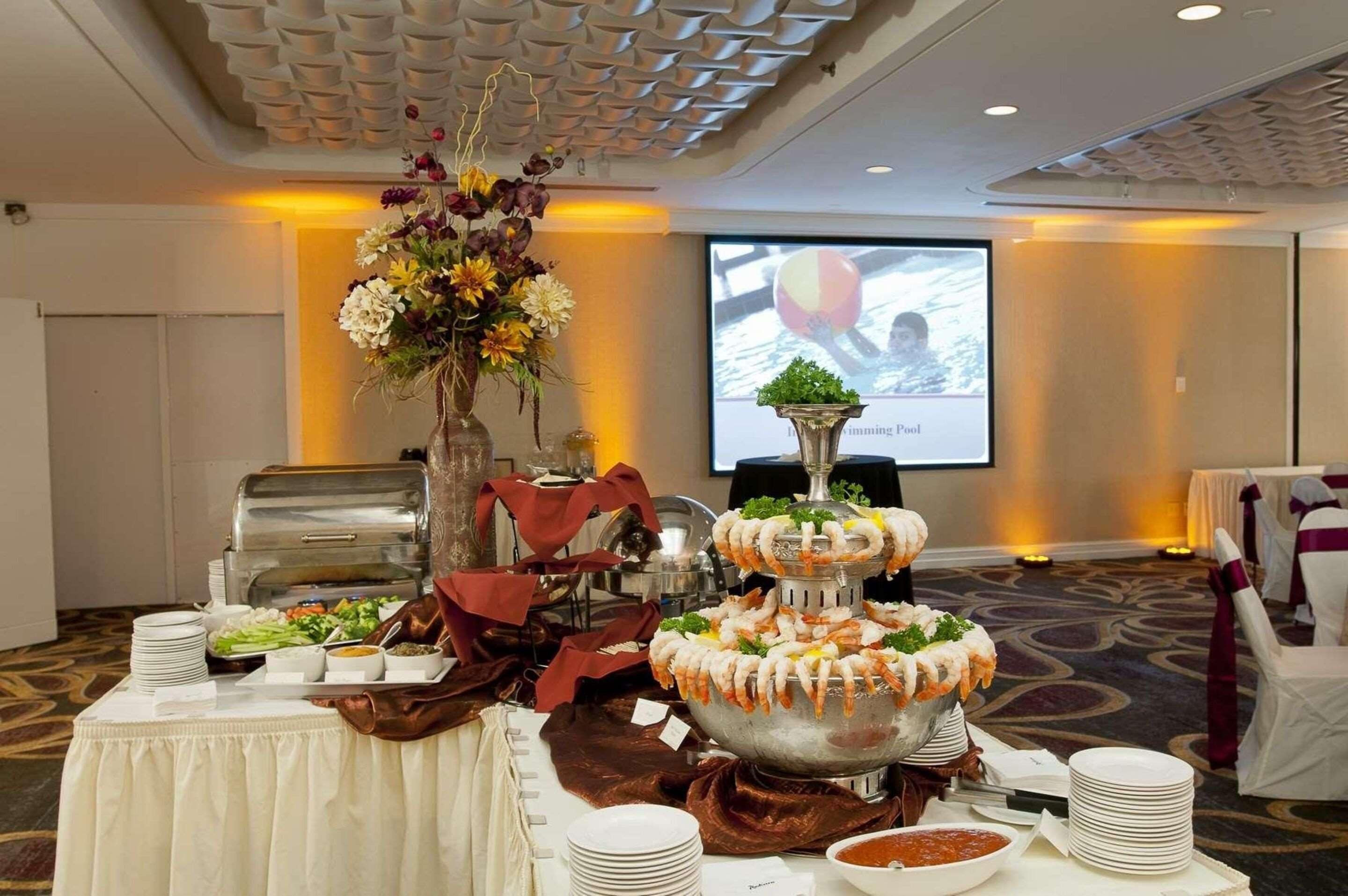 A buffet setup with a central shrimp fountain, salad, and various dishes on a table.