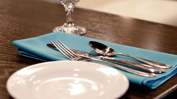 Une table à manger avec une assiette blanche, une serviette bleue et des couverts.